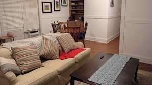 A living room with a beige sofa, patterned pillows, a wooden coffee table, and a white refrigerator.