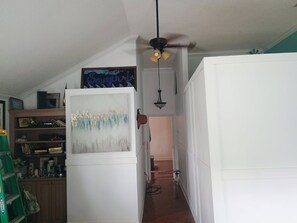A hallway with a white refrigerator, a ceiling fan, and a sign on the wall.