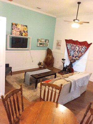 A living room with a television, a wooden coffee table, a sofa, and a dining table with chairs.
