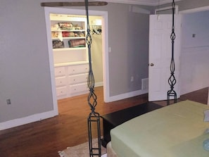 Een slaapkamer met een bed, een kledingkast met daarin hangende kleding en een deur.