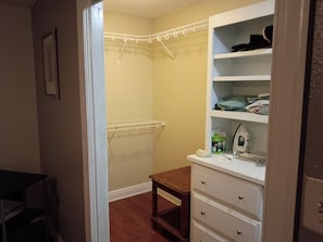 A walk-in closet with shelves, a hanging rack, and a small table.