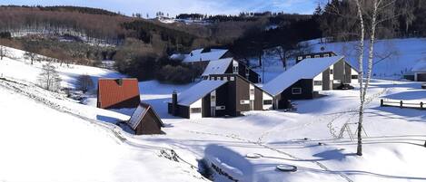 Ein schneebedecktes Dorf mit traditionellen Holzhäusern und einem Gebäude mit rotem Dach.