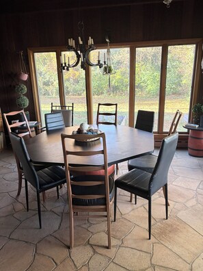 A dining area with a large round table, six chairs, and a chandelier.