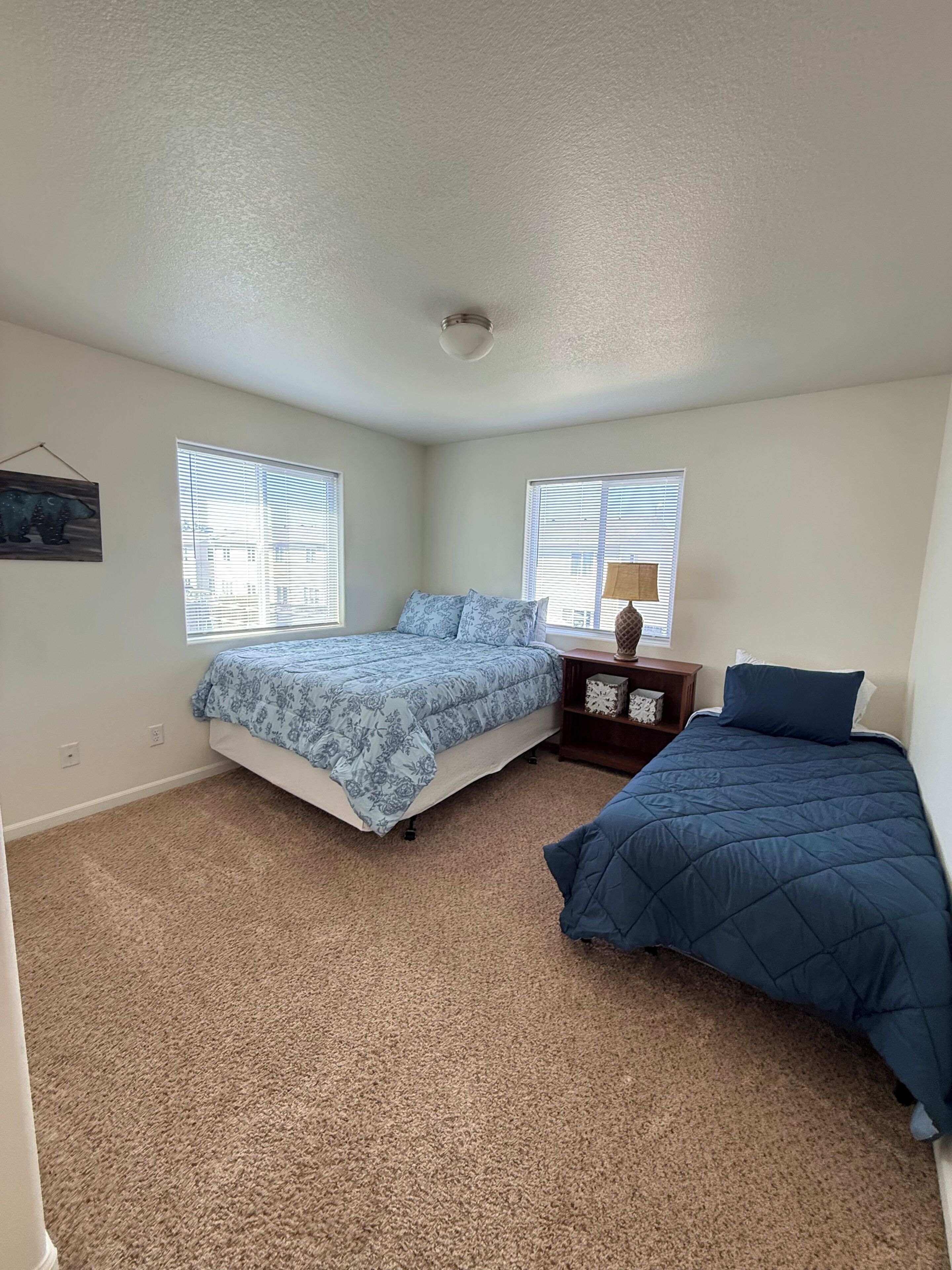 A bedroom with two beds, a ceiling fan, and a nightstand with a lamp.