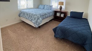 A bedroom with two beds, a ceiling fan, and a nightstand with a lamp.