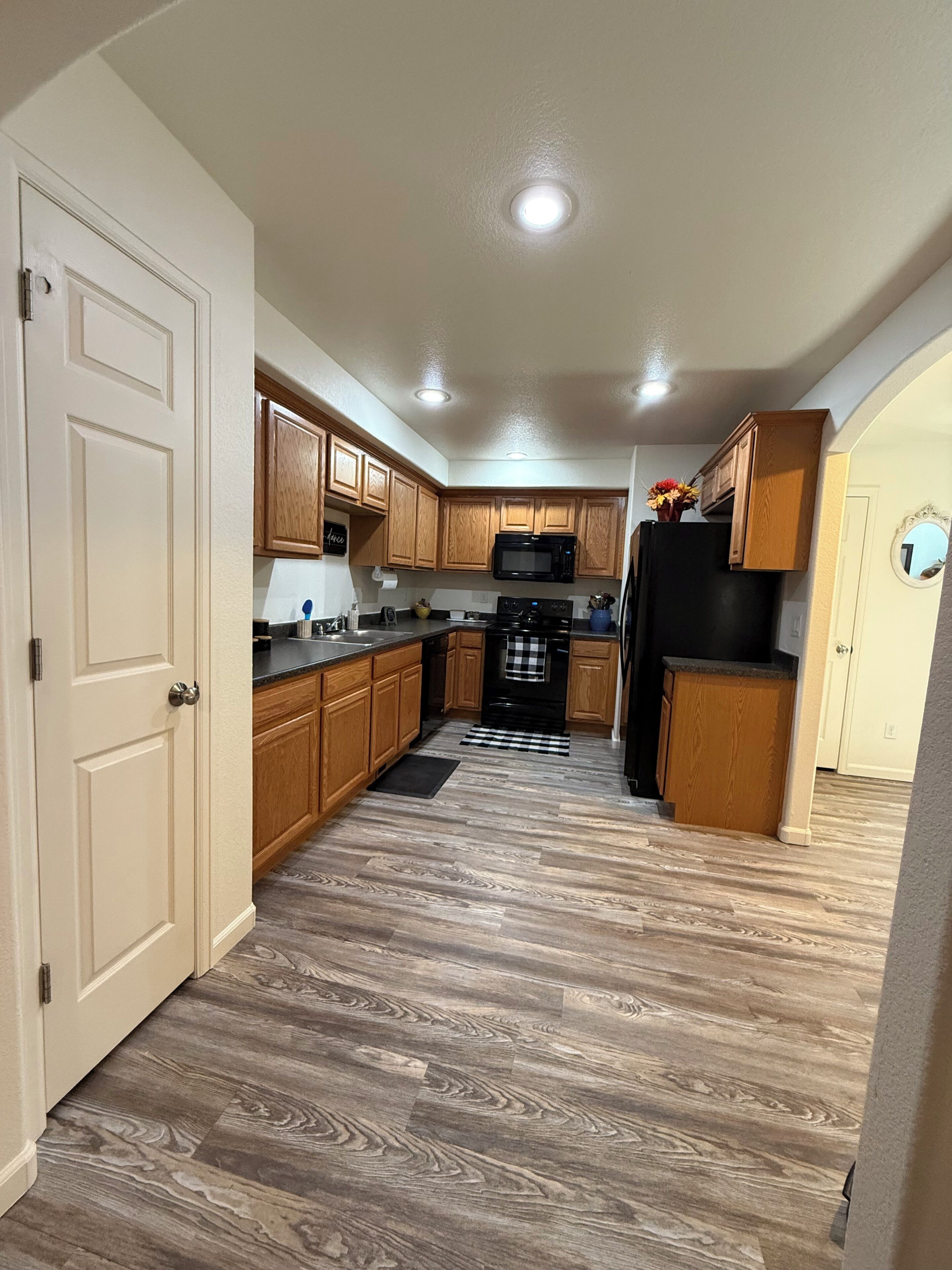 A kitchen with wooden cabinets, a black refrigerator, a microwave, and a black stove.
