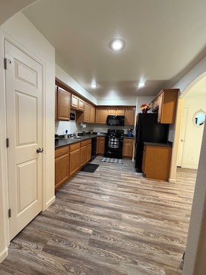 A kitchen with wooden cabinets, a black refrigerator, a microwave, and a black stove.