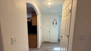 A hallway with a wooden floor, white walls, and a door at the end.