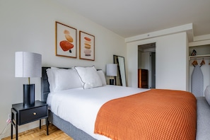 A modern hotel room with a bed, two bedside lamps, a nightstand, a wardrobe, and a mirror. - Blueground | Prudential / St. Botolph, view, nr Boston Public Garden (Boston)