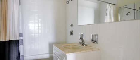 Un baño con bañera, lavamanos, ducha y espejo.