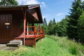 A wooden cabin with a porch and a small step leading to the entrance. - The Raven (Crianlarich)