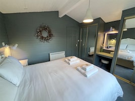 Habitación de hotel con cama, espejo, radiador y lámpara fijada a la pared.
