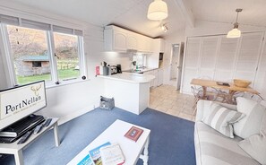 A compact living space with a kitchenette, a dining area, and a seating area with a sofa and a coffee table. - The Lapwing (Crianlarich)