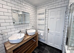A bathroom with two sinks, a mirror, a towel rack, and a door. - The Lapwing (Crianlarich)