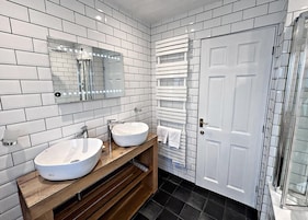 Un baño con dos lavamanos, un espejo, un perchero para toallas y una puerta.