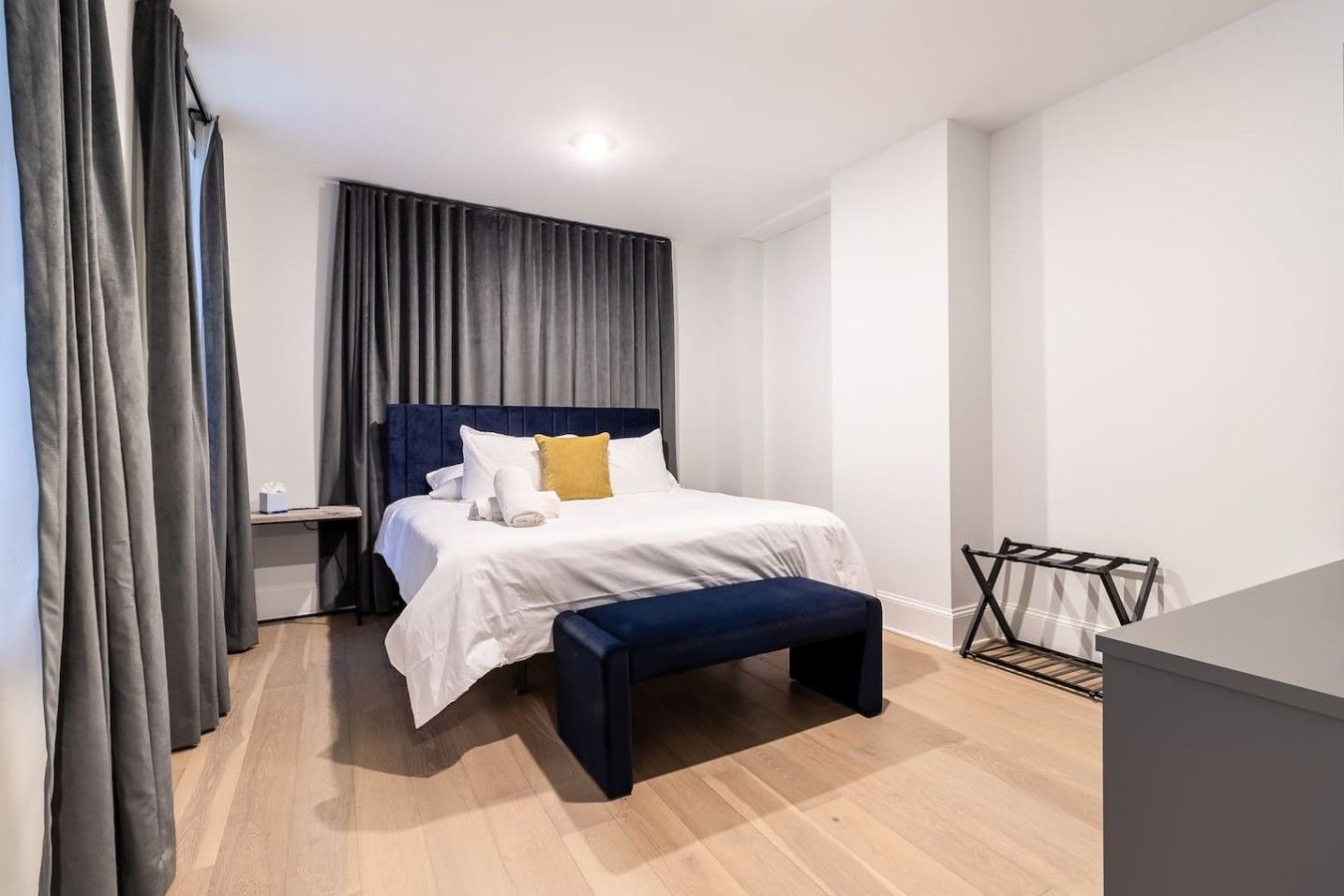 Een moderne hotelkamer met een bed, nachtkastje en een bankje.