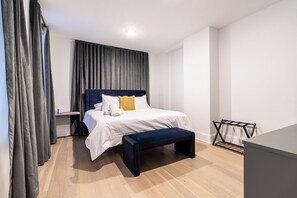 A modern bedroom with a bed, bedside table, and a bench. - Thena Hotel - Beautiful 1 Bedroom (Philadelphia)