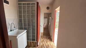 Un pasillo estrecho con una zona de cocina a un lado, que incluye un lavamanos y armarios.