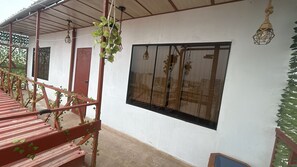 Un espacio al aire libre cubierto con una escalera de madera, un ventanal con vistas y plantas colgantes.