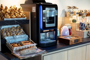 Un coin café équipé d’une machine à café, de viennoiseries et de pain.