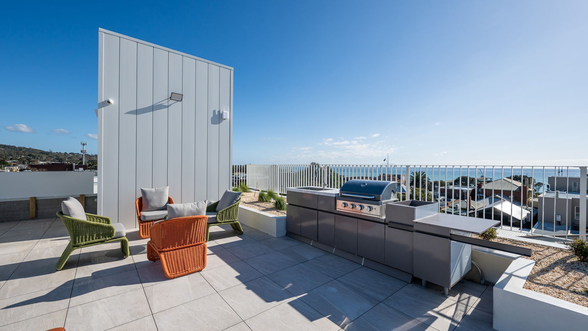 A rooftop terrace with outdoor seating, a barbecue grill, and a view of the sea.