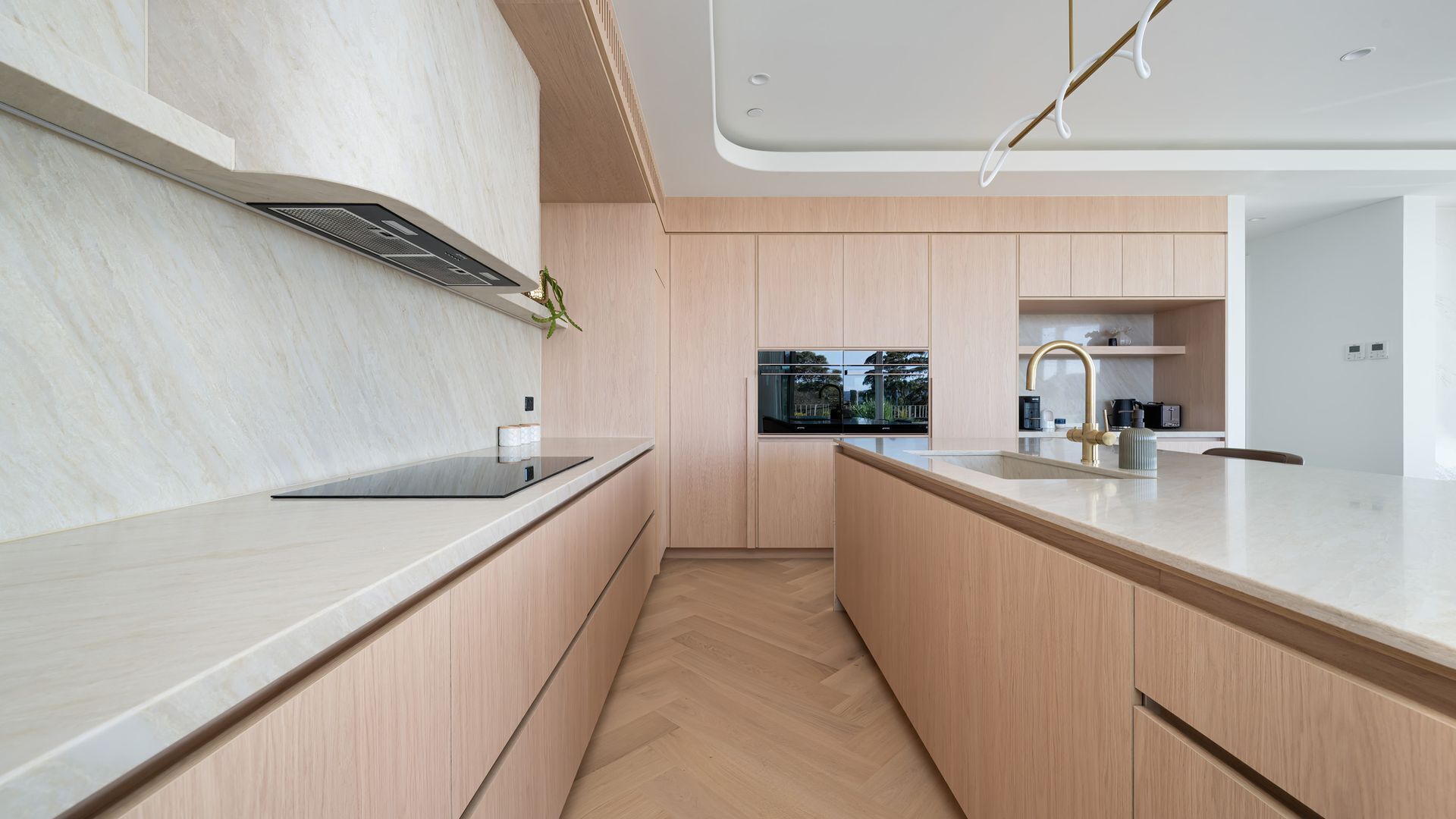 A modern kitchen with a central island, wooden cabinetry, and a built-in oven.