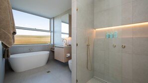 Ein modernes Badezimmer mit einer freistehenden Badewanne, einer Dusche und einem Fenster mit Blick.