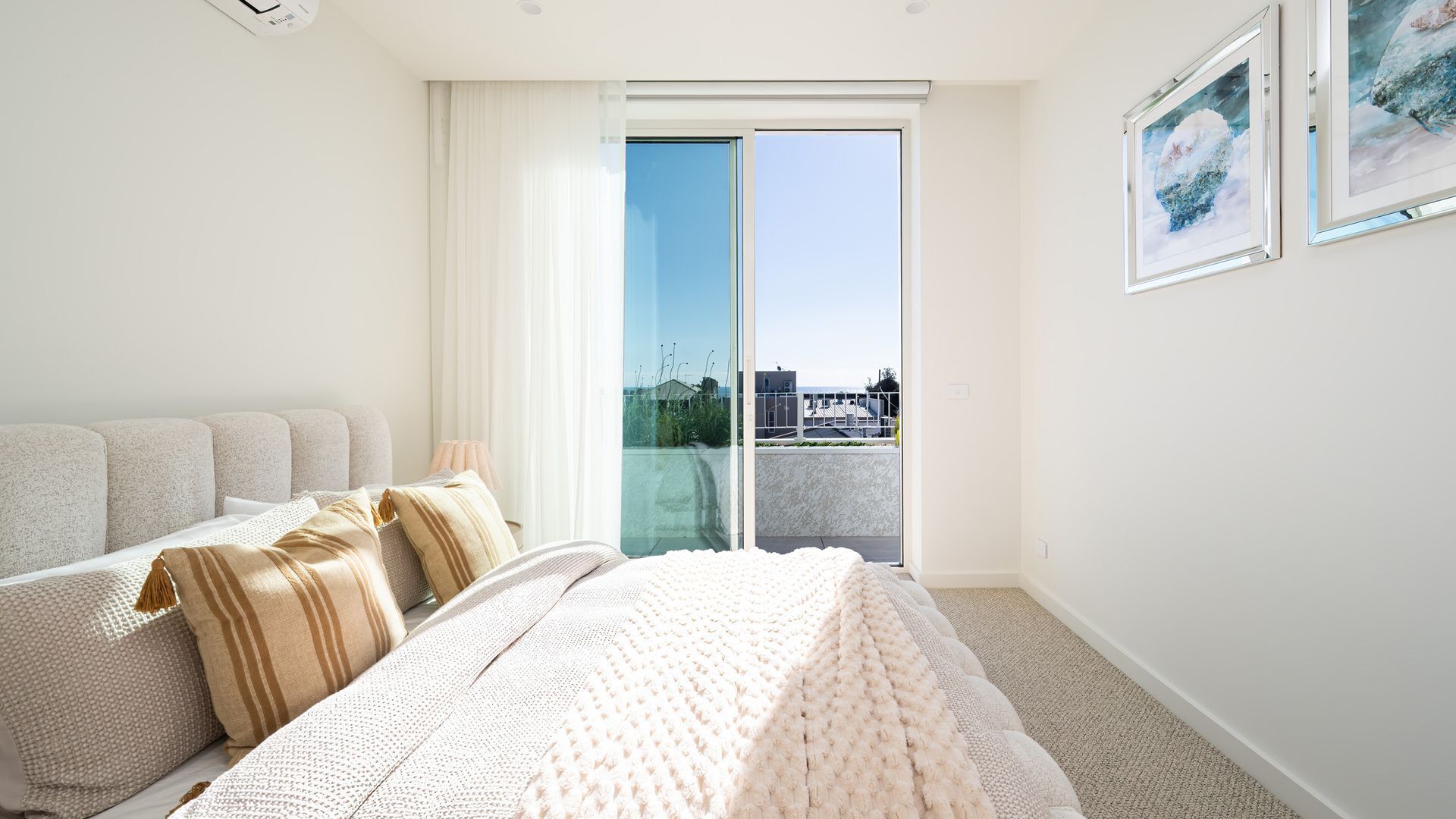 A hotel room with a bed, a sofa, a large window, and a view of the city.