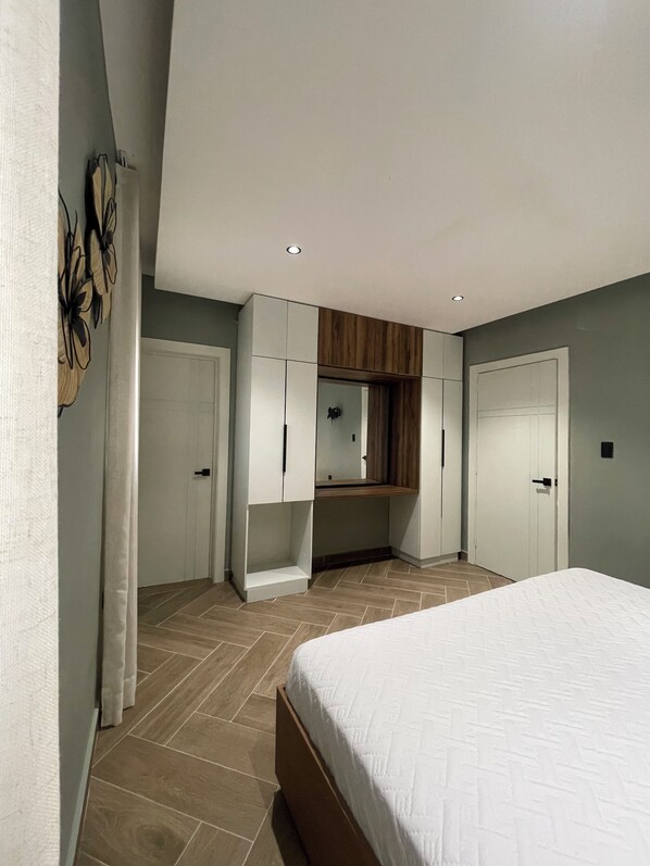 A bedroom with a bed, a wardrobe, a mirror, and a built-in shelf.