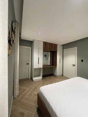 A bedroom with a bed, a wardrobe, a mirror, and a built-in shelf. - Vrbo Property (Higuey)