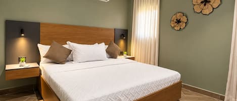 A modern bedroom with a large bed, wooden headboard, two bedside tables with lamps, an air conditioning unit, and decorative wall art.