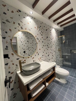 A modern bathroom with a freestanding sink, a round mirror, and a shower enclosure. - Vrbo Property (Higuey)
