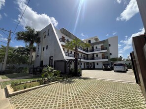 A multi-story residential building with a gated entrance, a paved driveway, and a landscaped garden area. - Vrbo Property (Higuey)