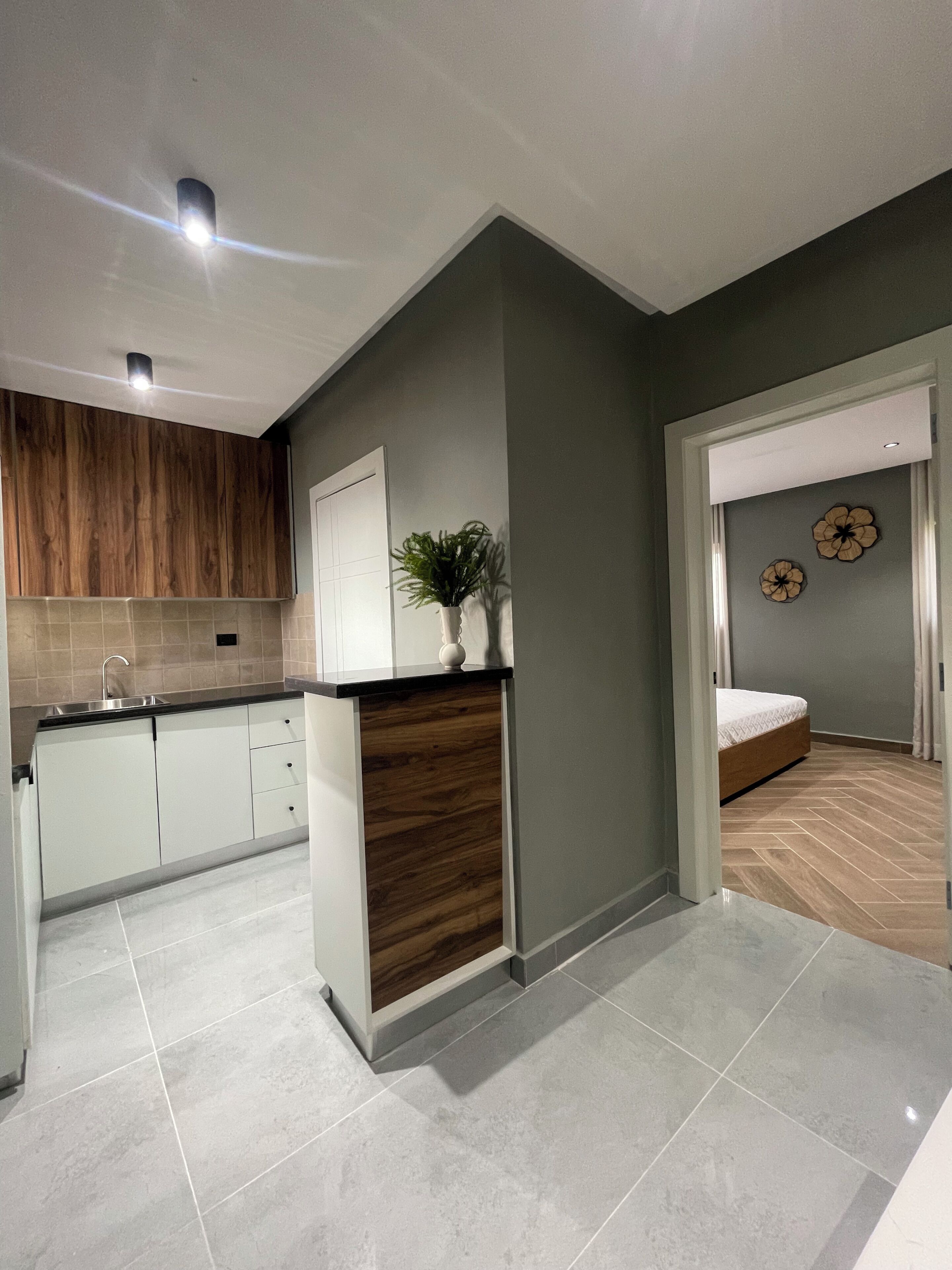 Una cocina moderna con armarios blancos, un revestimiento de pared de madera y una planta en maceta.