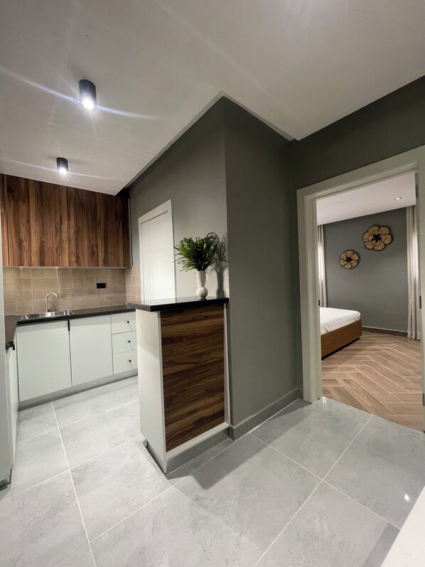 Una cocina moderna con armarios blancos, un revestimiento de pared de madera y una planta en maceta.