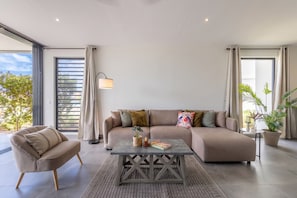 A modern living room with a sofa, armchair, coffee table, and potted plants. - Ground-Floor 2BR Condo · Pool steps away · Curaçao (Jan Kok)