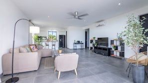 A modern living room with a sofa, coffee table, and a television. - Ground-Floor 2BR Condo · Pool steps away · Curaçao (Jan Kok)