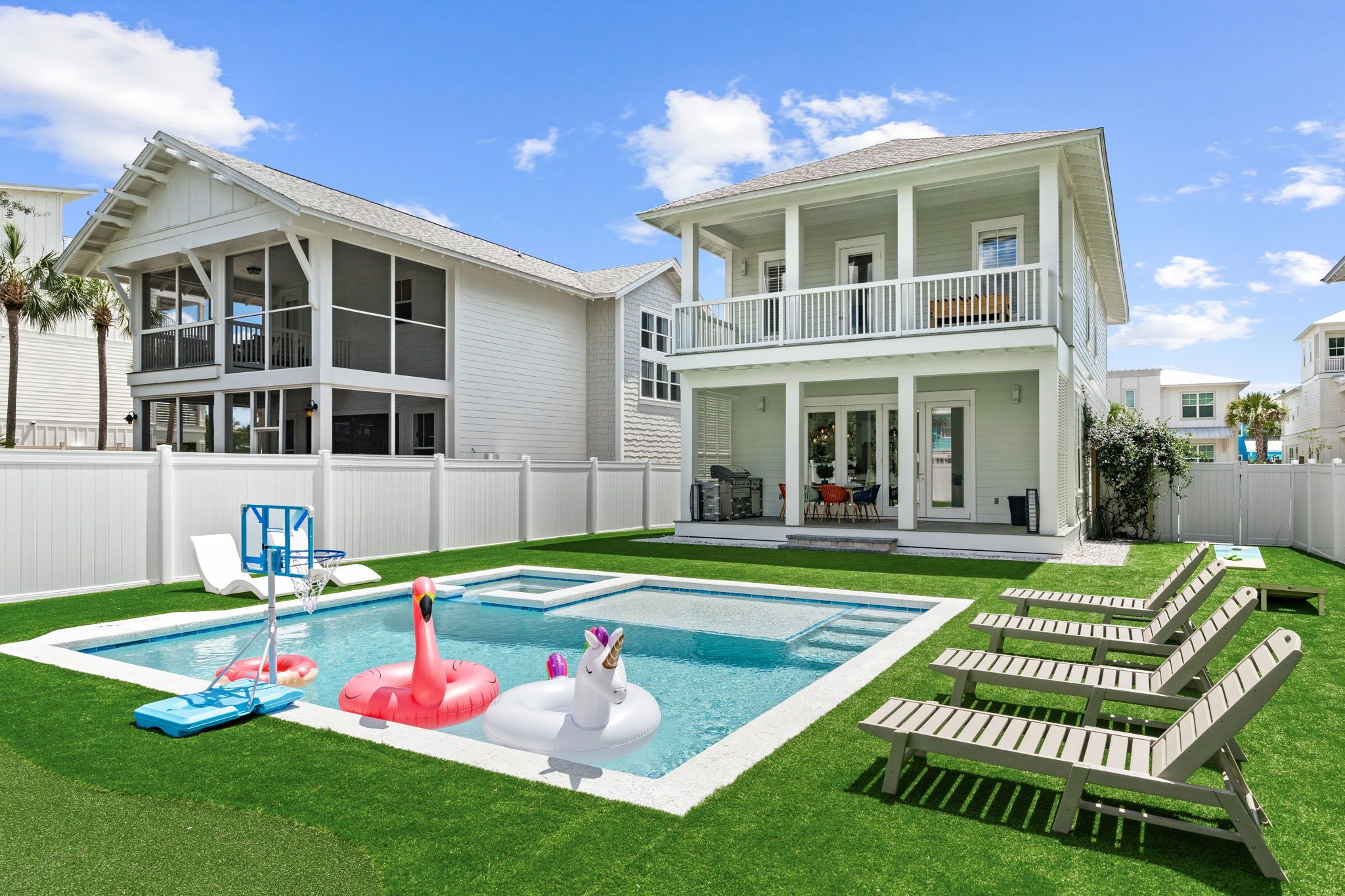 A two-story house with a swimming pool, a fenced yard, and outdoor furniture.