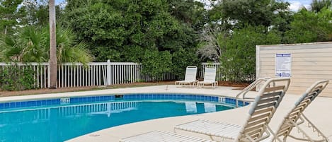 A swimming pool with lounge chairs and a fence.