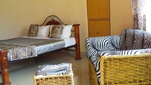 Una habitación con cama, sofá y sillón de mimbre.