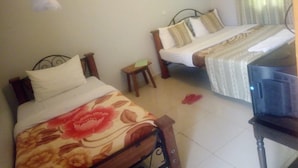 Habitación de hotel con dos camas, una mesita y un televisor.