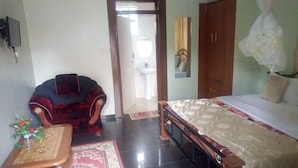 Una habitación con una cama, una silla, una mesa y una puerta que da a otra estancia.