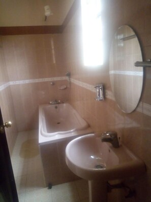 A bathroom with a bathtub, a sink, and a mirror. - Le Voyage Resort (Kitale)