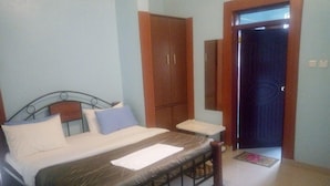 Un dormitorio con cama, armario de madera, mesita de noche y una puerta.