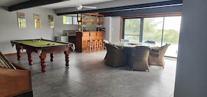 A pool table, bar area, and dining space with wicker furniture.