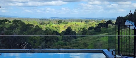 A swimming pool with a view of a green landscape and hills.