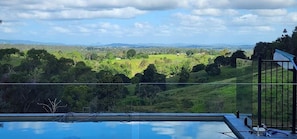 Une piscine offrant une vue sur un paysage verdoyant et des collines.