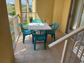 Ein Balkon mit Tisch und Stühlen, einem Geländer und Blick auf eine Straße und Grünflächen.