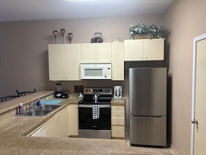 A kitchen with a stainless steel refrigerator, a microwave, a stove, and a sink. - 2-bedroom/ 3 bed condo at SouthPadre Island (South Padre Island)