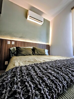 A hotel room with a bed, a wall-mounted air conditioner, and a power outlet. - Pool-Vacation-Jobs-Grills - PUERTO CARMA (Las Juntas)